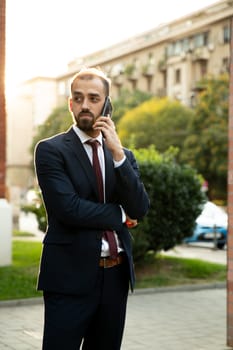 Successful businessman talking on the phone at sunset. Business style and street