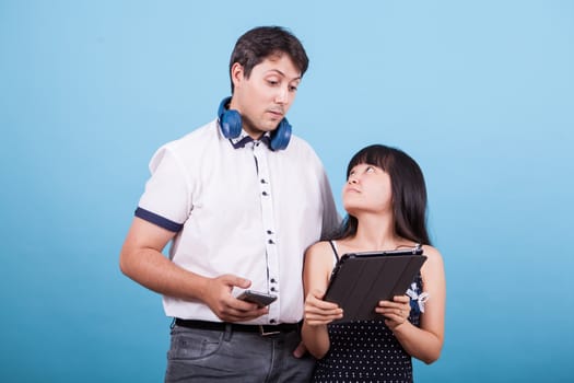 Asian girlfriend showing something on tablet to her caucasian boyfriend. Interracial couple.