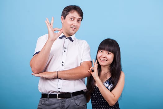 Smiling interracial couple showing ok hand gesture. Asian girlfriend.