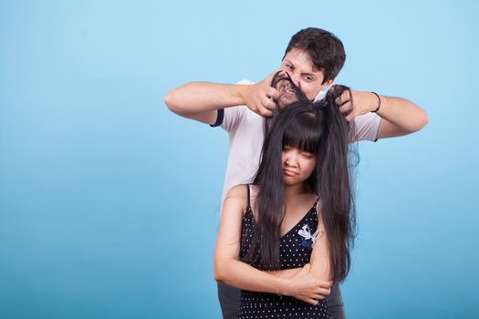 Upset asian girlfriend and caucasian boyfriend teasing her. Interracial couple.