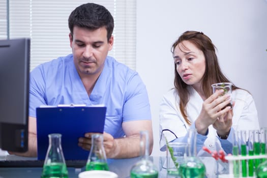 Young assistant writing notes on his notepad in a research lab. Female scientist.