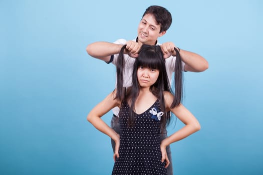 Angry asian girl while boyfriend is pulling her hair. Interracial couple.