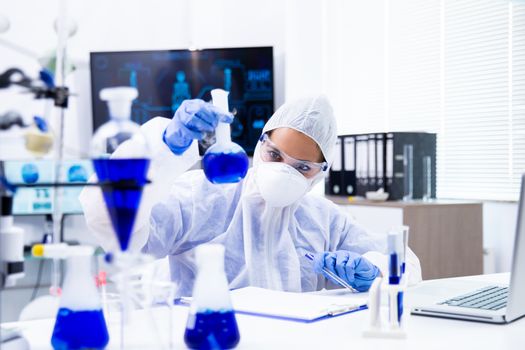 Researcher follows blue liquid from a tube and prepares to make some notes