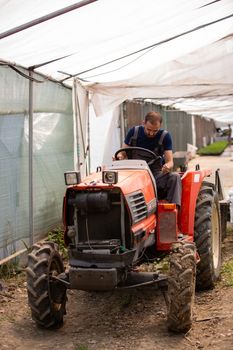 Worker trying to start a tractor at the greenhouse.