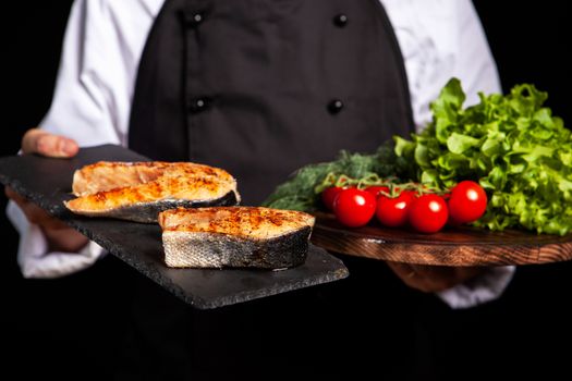 Chef presenting two countertops with salmon and vegetables. Clouse-up photo
