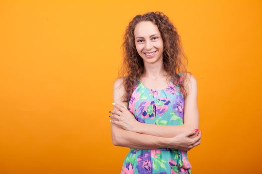 Cheerful young woman keeping her hands crossed and smiling in studio. Caucasian woman.