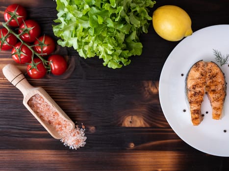 Top view of piece of lemon, salmon and tomatoes, all spread out on the table. White plate pepper and salt