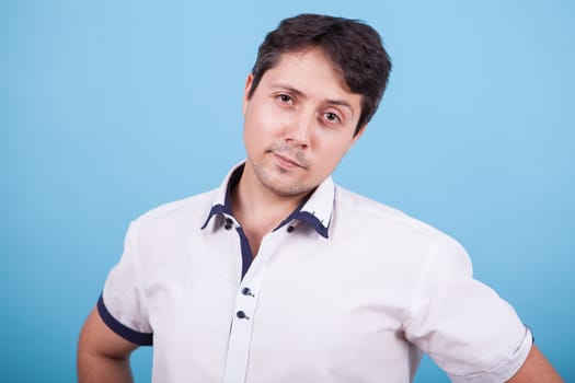 Caucasian young man looking at the camera in studio with raised eyebrow. Facial expression,