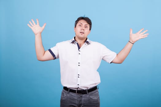 Confused caucasian young main riasing his hands in the air. Male in white shirt.