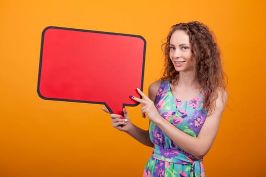 Caucasian woman holding on her right an empty bubble thought sign in studio over orange background.