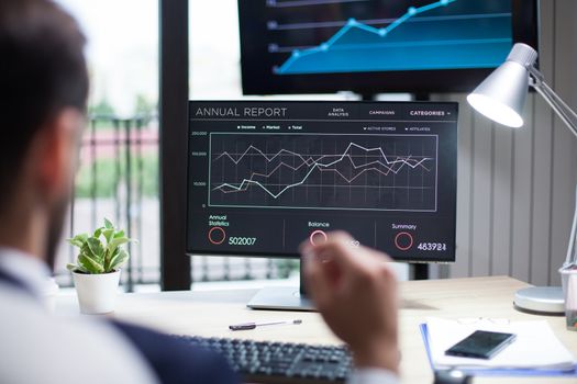 Diagrams displayed on computer monitor analysed by young businessman. Graphics on monitor.