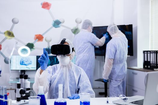 Scientist with virtual reality goggles for chemistry test in a modern lab. Blue liquid in test tubes.