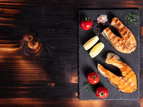 Top view with salmon rings arranged on a stone platter. Tomatoes and lemon