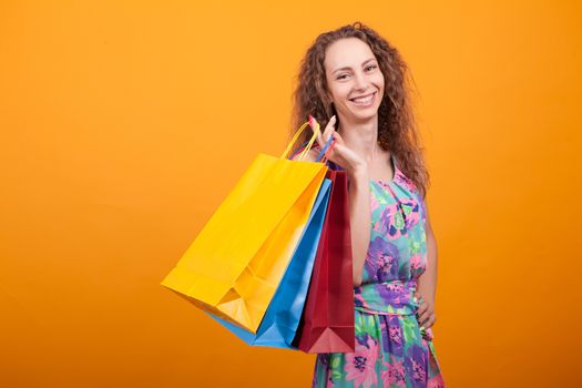 Woman with a big smile in studio holding shopping bags. Gorgeous and stylish woman.