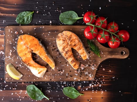 Top view of salmon spread on a wooden bottom and with some spinach leaves around. Salt and pepper together with tomatoes