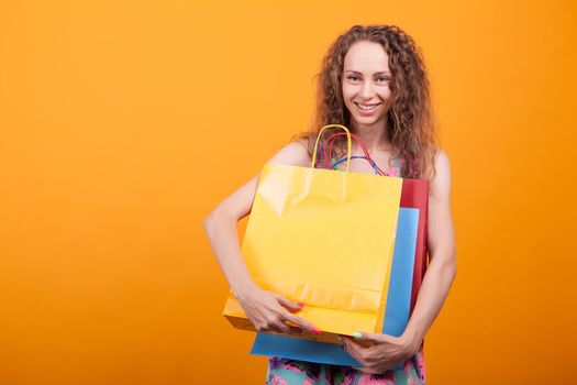 Joyful young lady smiling with shopping bags in her hands. Stylish caucasian woman over orange background.