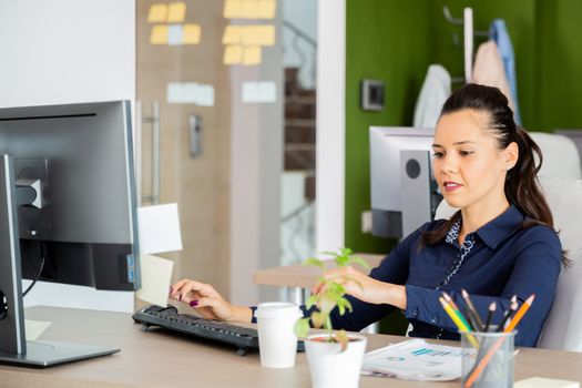 Girl stands in front of the computer. She looks at the screen