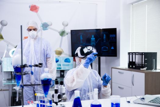 Female scientist wearing virtual reality glasses pointing,. Test tubes with smoking blue liquid.