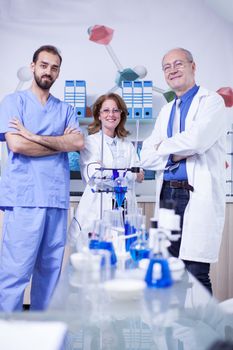 Portrait of researchers team with arms crossed smiling to the camera. Scients lab. Protection gear.
