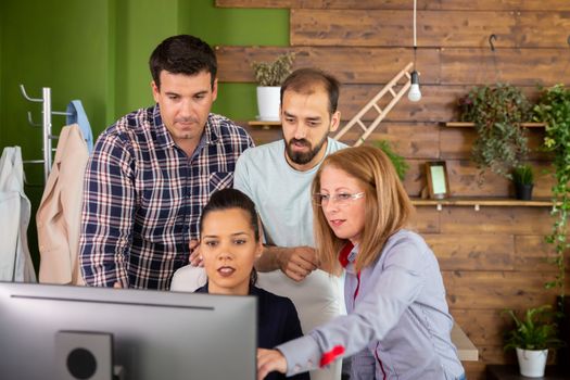 Group of creative people brainstorming in front of PC screen. Cozy office