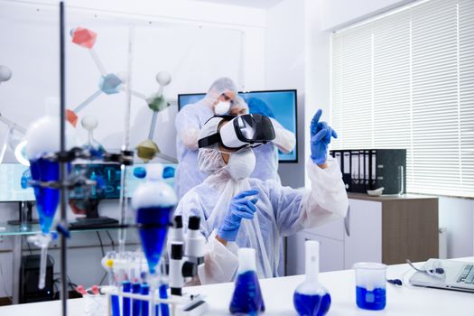 Female researcher using virtual reality goggles in her experimental test. Team of scientist in modern laboratory.
