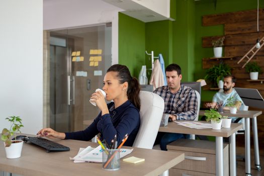 Beautiful caucasian worker sipping coffee while working on the computer