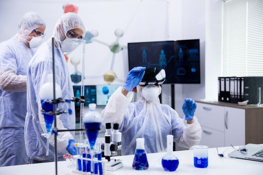 Team of scientist using virtual reality goggles for scientific research in their laboratory. Smoking blue liquid.