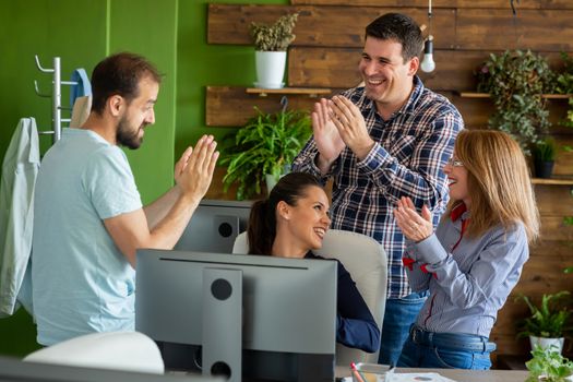 Business people in cozy office clapping at the success of new project. Teamwork and success
