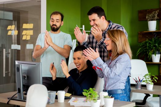 Happy entrepreneurs celebrating a big sale. Cozy creative company office