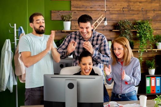 Business partners in start-up office celebrating a big sale. They all are happy and clapping