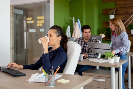 Gorgeous businesswoman drinking coffee in busy start-up company office