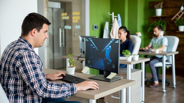 Start-up worker plays video games on computer.While his colleagues work