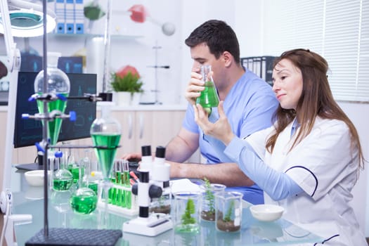 Middle age woman with her assistant working in a research lab for microbiology. Test tubes.