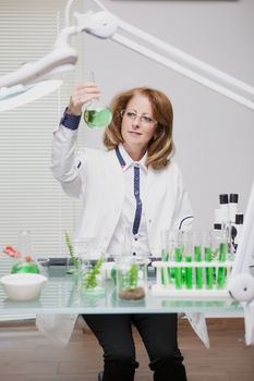 Portrait of middle age woman working in microbiology industry. Female scientis in laborator. Test tubes.