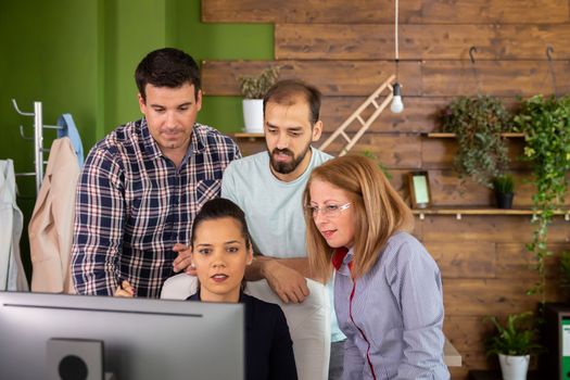 Middle age manager female looking into computer screen while checking the work of her young team