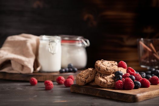 Freshly baked chocolate chips with tasty forest fruits on wooden plate. Tasty raspberry and blueberries.