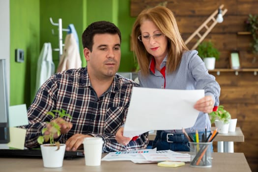 Man and female office workers looking at documents in start up company office