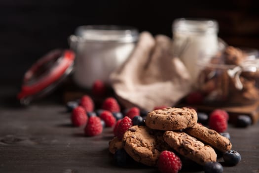 Rustic wooden table full of delicious chocolate chips with tasty bluebarries. Declious treat.