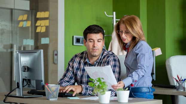 Two employees are looking at a sheet.Modern office