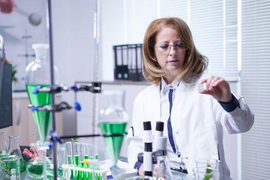 Female scientist in research lab making a test on a sample of cells. Qulity inspection.