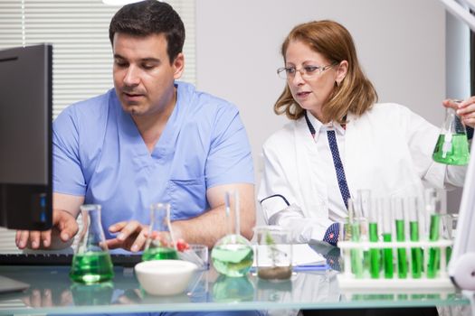 Photo of young assistant introducing the data that the leading scientist it's telling him. Research lab. Microbiological analysis.