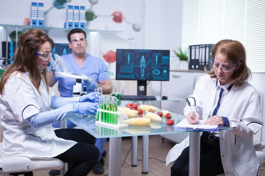 Caucasian female scientist writing down notes after ending quality inspection on strawberries. Strawberries analysis.