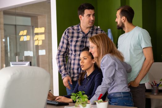 Two young assistants having a conversation while their managers are looking into computer monitor. Team discussing.