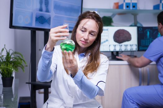 Modern science in a research lab with a middle age female scientist. Young male scientist working in the background.