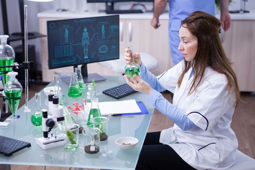 Mature scientist working with a green solution in a research lab. Modern technology.