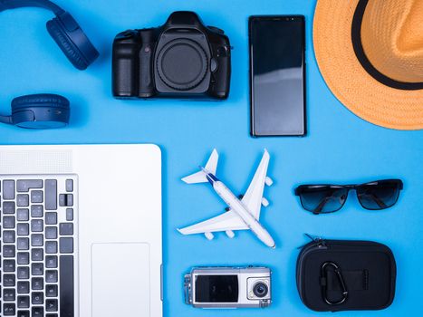 Flat lay traveler accessories over blue background. Modern photograper accessories. Orange hat.