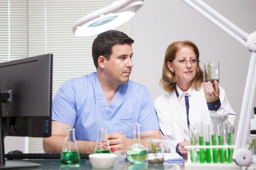 Young scientist learning from advanced female scientist in research laboratory. Test tubes.
