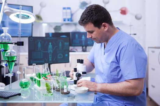 Young microbiologist working on his microscope in a research lab. Chemistry lab.