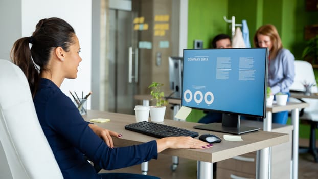 Businesswoman looks over the annual report figures in front of a computer
