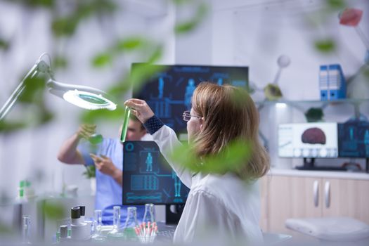 Female scientist holding and looking at a sample of liquid in a test tube. Academic scientist.